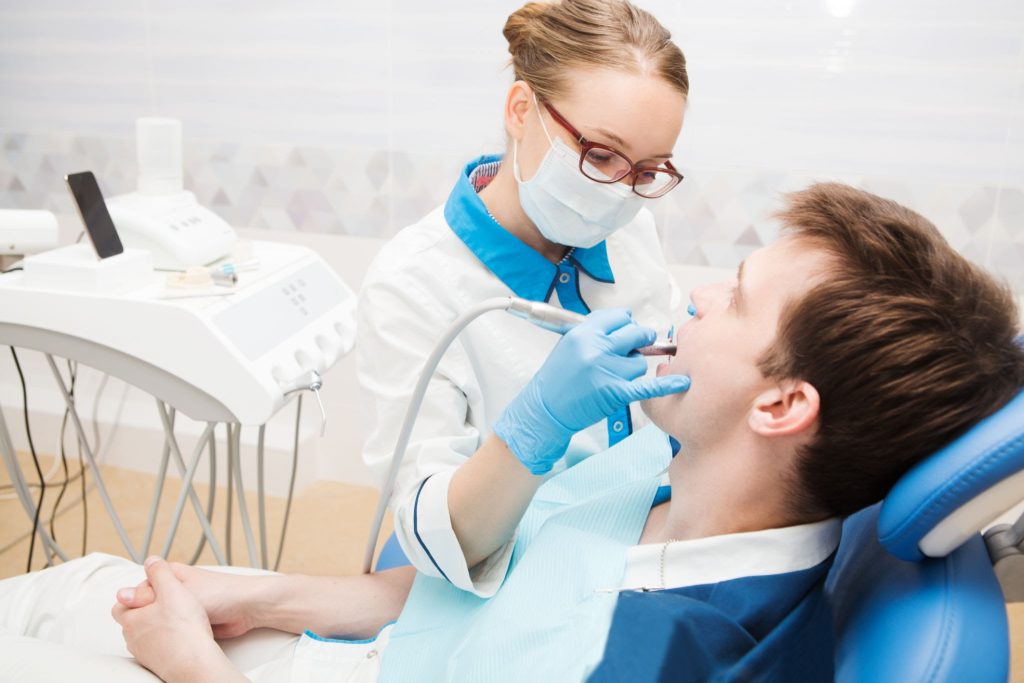 Dentist examining and working on young patient.